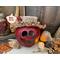 A fall apple decoration that is a real gourd with a happy face  carved into it. This gourd is named Cora and has a rustic handmade hat